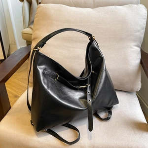 Chic black PU leather hobo bag with gold hardware shown on a beige lounge chair