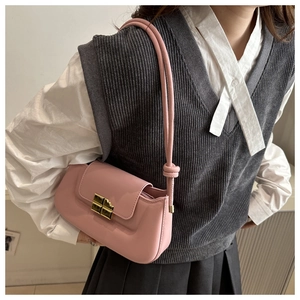 Detail of pink glossy patent leather saddle bag with gold metal clasp and knot strap