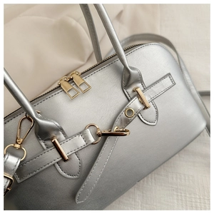 Close-up of silver vintage bowling bag with gold zippers and premium metallic leather texture