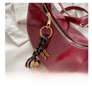 Macro detail of wine red crescent bag with textured leather and gold-tone charm