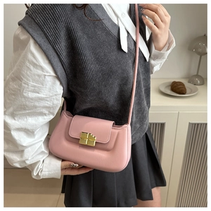 Pink baguette bag with gold metal buckle detail shown in a stylish minimalist setting