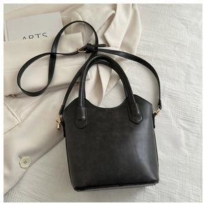 Macro shot of black leather bucket bag showing golden hardware and sleek matte texture