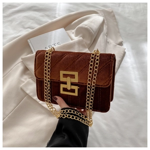 Detail of brown velvet crossbody bag featuring diagonal quilting and gold chain strap