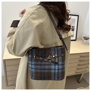 Detailed macro of vintage blue plaid wool bucket bag with premium leather trim and gold buckles