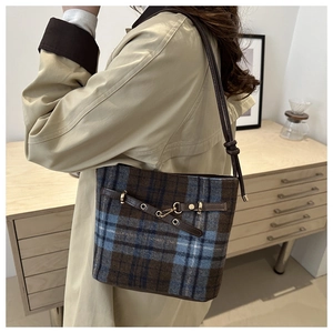 Detail of vintage plaid bucket bag with brown leather strap and metal buckle closure