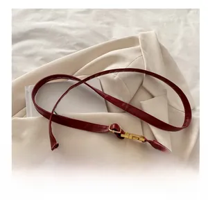Detail of the burgundy leather shoulder strap with vintage gold buckle on a cream blazer