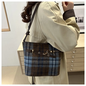 Detail of vintage british style plaid bucket bag with brown leather strap and metal buckle
