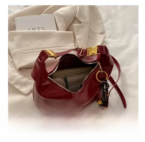 Detail view of burgundy leather crescent bag interior with gold buckle and woven strap