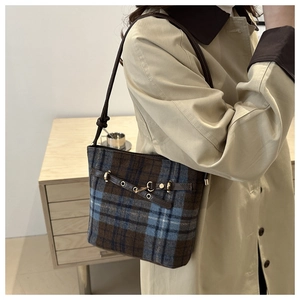 Detail of vintage plaid bucket bag with brown leather accents and golden metal hardware