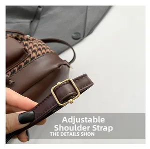 Detail view of adjustable brown leather shoulder strap with gold metal buckle and stitching