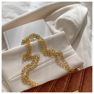 Close-up of golden metal chain strap and brown velvet crossbody bag with quilted pattern