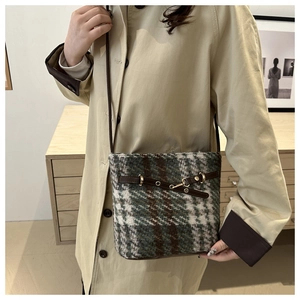 Close-up of vintage plaid tweed bucket bag with leather strap and golden metal buckle