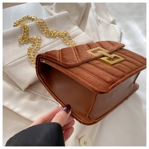 Detail view of brown velvet crossbody bag featuring golden buckle and vertical quilting