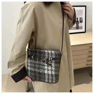 Close-up of retro tweed bucket bag with green plaid pattern and leather details