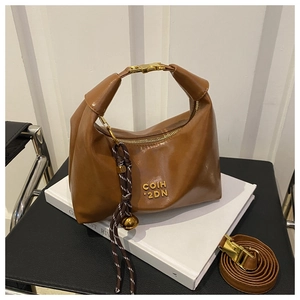 Detail view of brown leather dumpling bag with gold buckle and woven bell charm