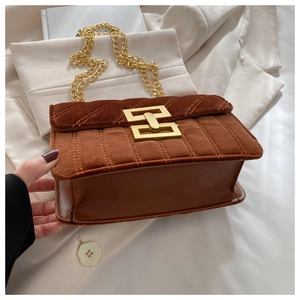 Detail of brown suede crossbody bag with vertical quilting and gold chain strap