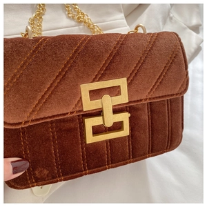 Detail of brown velvet crossbody bag featuring quilted texture and gold metal buckle