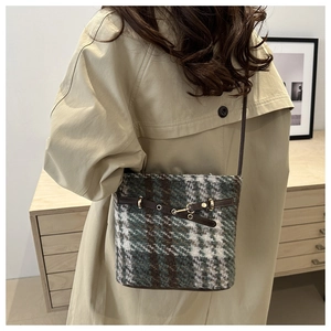 Detail of vintage plaid bucket bag with tweed fabric and leather strap on model