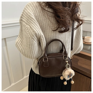 Detail of vintage brown leather pillow bag with cute plush sheep charm and crossbody strap