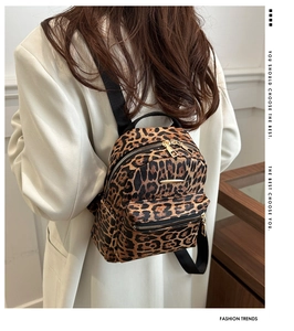 Side view of woman wearing a mini leopard print backpack with gold zipper and metal logo