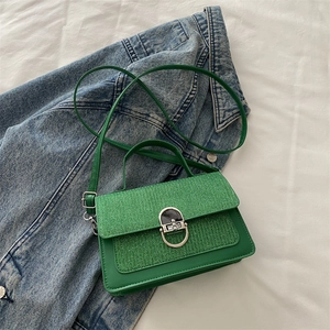 Green leather and tweed crossbody bag with silver D-ring lock on denim background