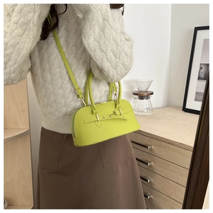 Fluorescent yellow-green handbag with metal lock shown in a warm indoor lifestyle setting