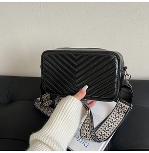Détail du sac bandoulière noir matelassé en V avec large bandoulière à motifs géométriques