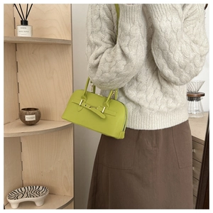 Close-up of lime green retro bowling bag with buckle detail on a minimalist shelf