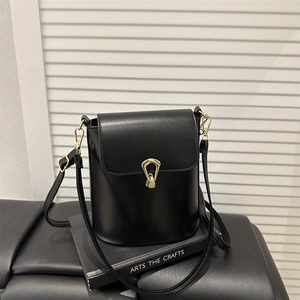 Minimalist black bucket bag with smooth leather finish and unique gold metal lock