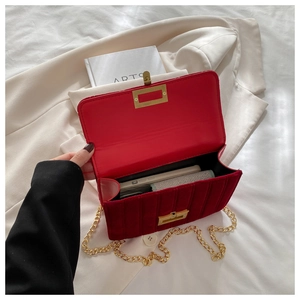 Detailed view of red velvet crossbody bag with gold chain strap and vertical quilting