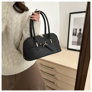 Detail of a black bowling bag with gold buckle hardware in a home interior setting