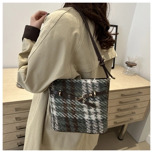 Detail of tweed bucket bag with dark brown leather straps and metal eyelet accents
