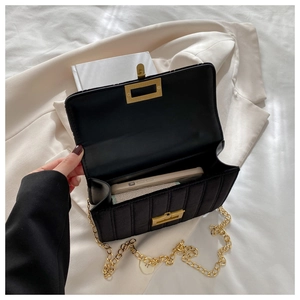 Detail view of black quilted crossbody bag showing gold twist lock and interior space