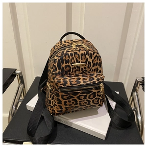 Detail of leopard print mini backpack showing gold-tone zippers and metallic logo plate