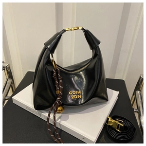 Detail view of black moon bag with gold clasp and leather shoulder strap on a book