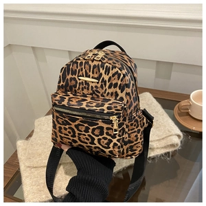 Detail of mini leopard print backpack featuring golden hardware and black nylon straps