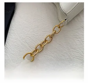 Close-up of golden metal chain link hardware on elegant white PU leather shoulder bag