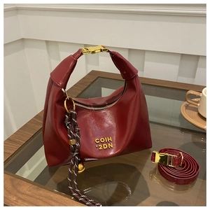 Detail of burgundy leather dumpling bag featuring gold zipper and braided tassel