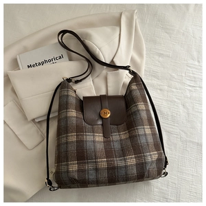 Detail of plaid tote bag featuring brown leather flap and gold metal N-letter buckle