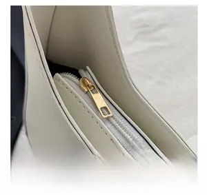 Detail shot of smooth cream leather texture and premium golden zipper on handbag