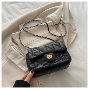 Detail of black quilted crossbody bag with gold chain strap and metal turn-lock closure