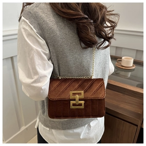 Detail of a brown velvet crossbody bag with quilted texture and gold metal buckle