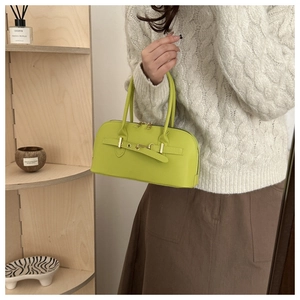 Detail of lime green bowling bag with gold hardware held by model in interior setting