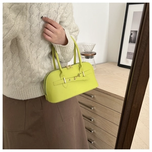 Detail of lime green shell bag featuring horizontal leather straps and gold metal buckles
