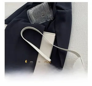 Detail showing the white shoulder strap and gold decorative chain of the crescent bag