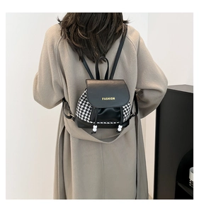 Detail of a black and white houndstooth mini backpack with fashion lettering on the flap