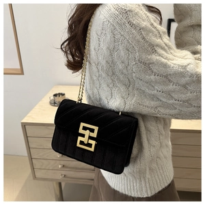 Detail of black velvet crossbody bag with quilted vertical stitching and gold chain strap