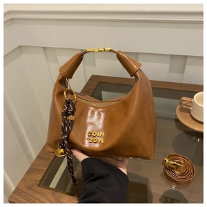 Close-up of brown oiled leather dumpling bag with gold logo and woven rope charm detail