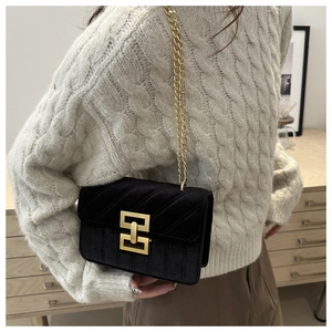 Detail of black velvet crossbody bag featuring gold geometric lock and quilted texture