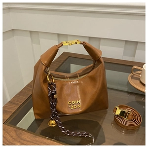 Close-up of dark brown crescent hobo bag with gold metal logo and bell charm detail